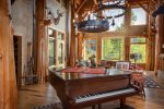 The great room features grand piano, gas fireplace & breathtaking views of Whitefish Mountain Resort.